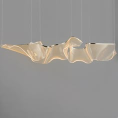 an artistic light fixture hanging from the ceiling in a room with grey walls and flooring