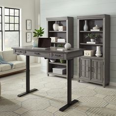 a computer desk with a laptop sitting on top of it next to a book shelf