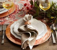 a table set with place settings, wine glasses and napkins on top of it