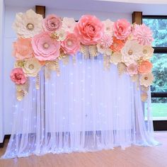 an arrangement of paper flowers on the back of a drape for a wedding ceremony