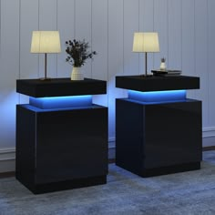 two black tables with blue lights on each side and a vase with flowers in the middle