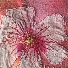 a close up of a flower on a piece of cloth with stitches and threads