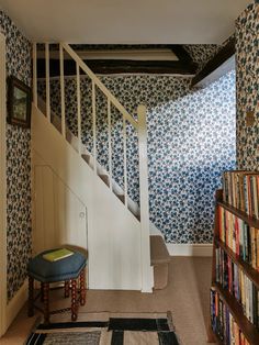 the stairs in this house are decorated with blue and white floral wallpaper, along with bookshelves