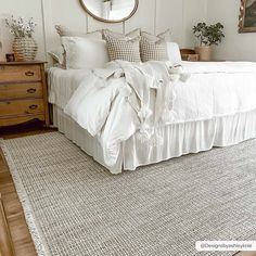 a white bed sitting in a bedroom next to a wooden dresser and mirror on top of a hard wood floor