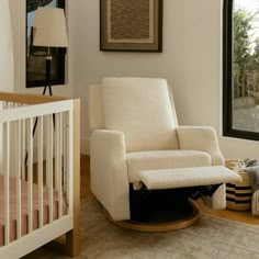 a baby's room with a rocking chair, crib and large window in it