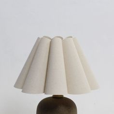 a table lamp that is on top of a wooden base with a white fabric shade