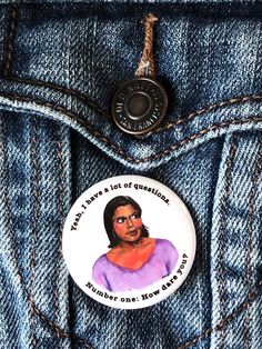 a button that is in the pocket of a jean jacket with an image of a woman's face on it