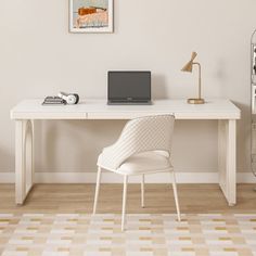 a white desk with a laptop computer on top of it next to a lamp and bookshelf