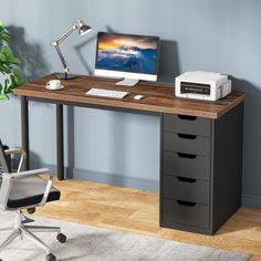 a computer desk with drawers and a printer on it in front of a blue wall