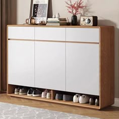 a white cabinet with several pairs of shoes sitting on it's sideboard next to a window