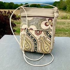 "A sweet  little bag specially made for all times where you need to have your phone(even the largest will fit)and a few other essentials . An excellent travel bag-it's flat and fits close to your body while leaving your hands free. Great for shopping,dancing or carrying a baby on your arm. Chenille Tapestry imported from Turkey combined with Cream Color Leather. A long adjustable Leather Strap. 6 \"Zipper Top opens to 1 large section with a small pocket that could hold a few credit card, plus a Portable Beige Shoulder Bag For Everyday Use, Beige Pouch Shoulder Bag With Mobile Phone Pocket, Beige Pouch Phone Bag For Daily Use, Rectangular Everyday Zipper Phone Bag, Beige Shoulder Phone Bag For Daily Use, Beige Tote Phone Bag With Adjustable Strap, Portable Square Pouch For Everyday Use, Beige Shoulder Phone Bag For Travel, Square Mobile Phone Pouch For Daily Use