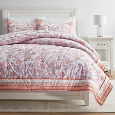 a bed with an orange and white comforter