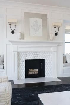 a white fireplace in a living room with pictures above it