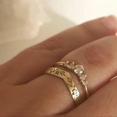 a woman's hand holding a gold ring with three stones on it and two leaves