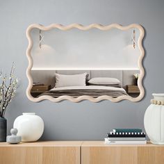 a bedroom with a large mirror on the wall next to a dresser and vases