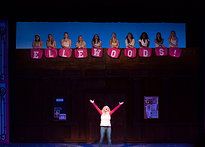 a woman standing on top of a stage holding her arms up in front of the audience