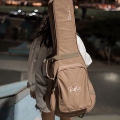 a woman carrying a guitar case on her back