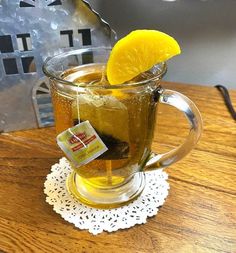 a glass mug filled with tea sitting on top of a wooden table