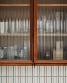 two wooden cabinets with glass doors in a kitchen