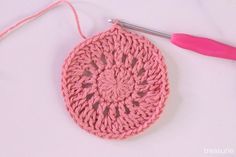 a crochet doily with a pink yarn ball next to it