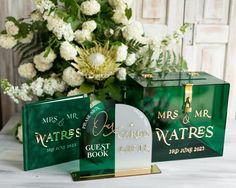 two green book cases sitting on top of a table next to a vase with white flowers