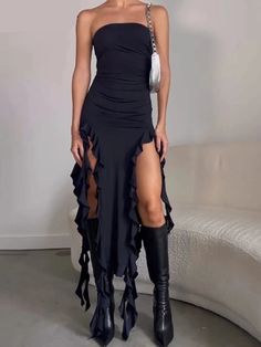 a woman in a black dress and high heeled boots posing for the camera with her legs crossed