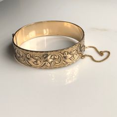 A vintage 9 carat rolled gold bangle. What a beautiful piece, with elegant leaf detailing and such a shine! CONDITION: Good condition, wear consistent with age and use. Please see photos for more detail. MARKED 9 CARAT ROLLED GOLD  INTERNAL SIZE: 180mm BANGLE WIDTH: 19mm BANGLE INTERNAL DIAMETER: 59mm / 53mm WEIGHT: 29.0 grams Vintage Yellow Gold Bangle Stamped 14k, Antique 14k Stamped Bangle As Gift, Classic Gold Etched Bangle, Classic Round Cuff Bracelet For Ceremonial Occasions, Classic Round Ceremonial Cuff Bracelet, Formal Cuff Bracelet With Intricate Design, Heirloom Cuff Bracelet With Intricate Design For Formal Occasions, Vintage Yellow Gold Cuff Bracelet With Intricate Design, Vintage Etched Yellow Gold Bracelets