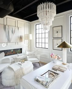 a living room filled with white furniture and a chandelier hanging from the ceiling