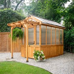 a wooden gazebo in the middle of a graveled area next to a fence