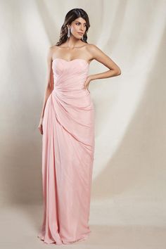 a woman in a strapless pink dress poses for a photo with her hands on her hips