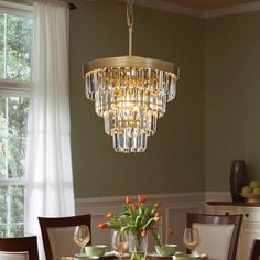 a chandelier hanging from the ceiling over a dining room table with place settings on it