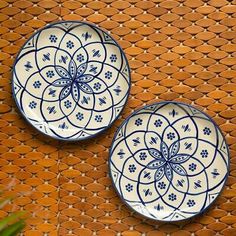 two blue and white plates sitting on top of a woven table cloth next to a plant