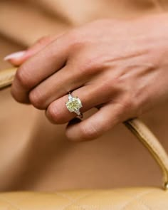 a close up of a person holding a handbag with a ring on it's finger