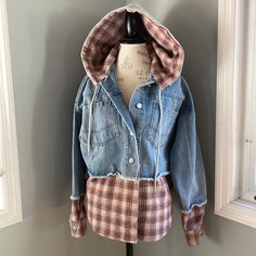 Perfect For Fall And Winter. This Jean Jacket Has Been Cut And Shows Exposed Raw Hems At The Sleeves And On The Body. Seen In Is A Brown Red And Blue Flannel Material That Looks Like The Jacket Is Fitting Over A Flannel Shirt. The Hood Is Removable. Silvertone Buttons, And Large Front Patch Pockets. Blue Hooded Denim Jacket For Fall, Oversized Hooded Denim Jacket For Fall, Blue Hoodie With Detachable Hood For Fall, Hooded Patchwork Denim Jacket For Fall, Plaid Cotton Hooded Jacket For Fall, Hooded Plaid Outerwear For Spring, Oversized Plaid Patchwork Outerwear, Spring Plaid Outerwear For Streetwear, Plaid Outerwear For Spring Streetwear