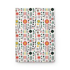 a white notebook with multicolored dots and circles on the cover, sitting against a white background