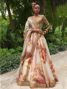 a woman standing in front of some trees wearing a dress with flowers on the skirt