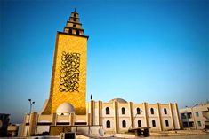 a tall yellow building with graffiti on it's side and a clock tower in the background