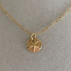 A sand dollar coin dangles from a delicate gold chain. The chain measures approximately 17 inches long is adjustable up to an inch shorter. Brass Coin Necklace With Round Pendant, Nickel Free Gold Round Disc Coin Necklace, Gold Coin Necklace With Adjustable Chain And Round Pendant, Gold Coin Necklace With Delicate Chain Pendant, Gold Hammered Round Pendant Charm Necklace, Gold Brass Coin Necklace, Nickel-free Gold Round Disc Coin Necklace, Nickel-free Gold Coin Necklace, Gold Pendant Coin Necklace With Delicate Chain