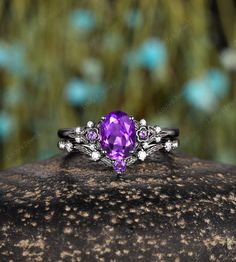 a ring with an amethorate and white diamonds on it sitting on top of a rock