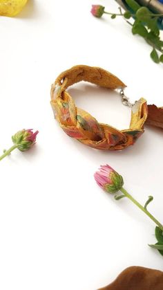 the bracelet is made from fabric and has flowers on it, along with other accessories