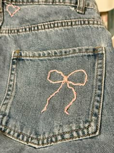 a pair of blue jeans with pink bows on the back of it's pocket