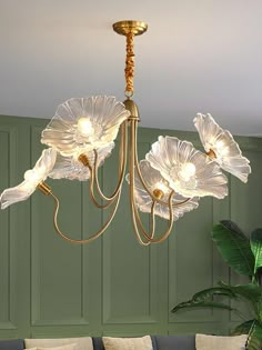 a chandelier hanging from the ceiling in a living room with green walls and couches