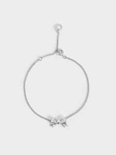 Our Paige bracelet is also available in a stunning silver finish. With its classic ribbon charm, this delicate piece is ideal for fashion lovers who want to embrace the coquette trend in an understated manner. Wear yours layered with other silver bracelets for a stylishly stacked look. Alternatively, style it with our matching Paige necklace and stud earrings for a complete set and polished look. Sterling Silver Adjustable Delicate Chain Bracelet, Chic Silver Chain Bracelet With Adjustable Chain, Adjustable White Gold Chain Bracelet, Adjustable Delicate White Gold Bracelet, Delicate Chain Sterling Silver Bracelet Gift, Feminine Adjustable Ribbon Jewelry, Elegant Sterling Silver Chain Bracelet For Party, Delicate Silver Chain Bracelet As Gift, Chic Jubilee Charm Bracelet As Gift