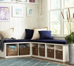 a blue and white bench with baskets on it in front of a window filled with pictures