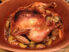 a roasted chicken in a bowl with vegetables