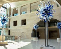 blue and white glass sculptures in the middle of a lobby with an arched window behind them