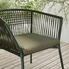 a green chair sitting on top of a wooden floor next to a tree in the background