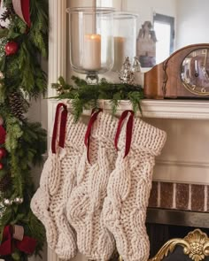 christmas stockings hanging from a mantel with candles