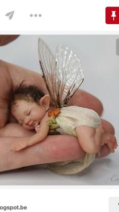 a person holding a tiny fairy doll in their hand