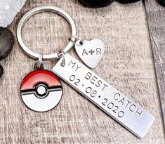 a metal keychain with a pokemon ball and heart shaped tag attached to it